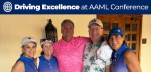 Five smiling people pose together indoors, dressed in golf attire. The group includes three women in matching blue polo shirts and two men, one in a pink floral shirt and the other in a tropical-print shirt holding a white cap.